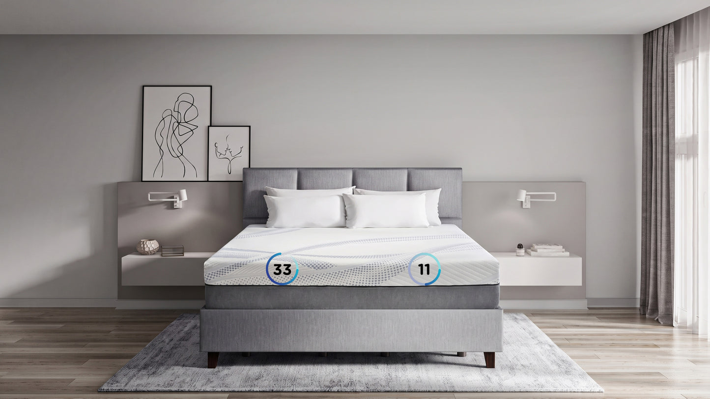 A modern gray upholstered bed with a padded headboard, dressed in white bedding, set in a minimalist bedroom with floating bedside tables, wall art, and a gray rug.
